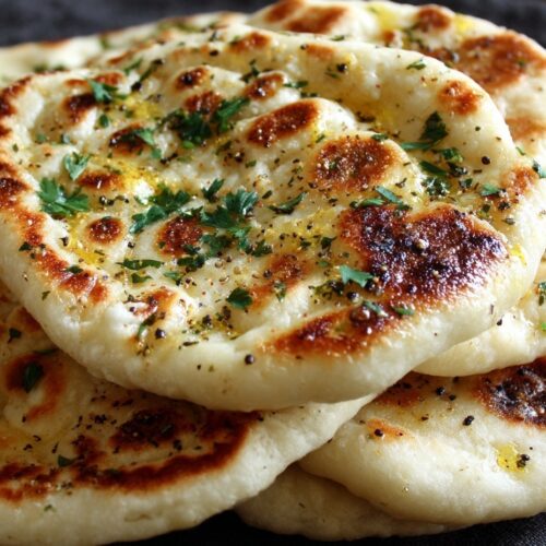 Stack of homemade Turkish bread Bazlama showing realistic golden-brown spots, butter glaze, and authentic puffed texture achievable at home